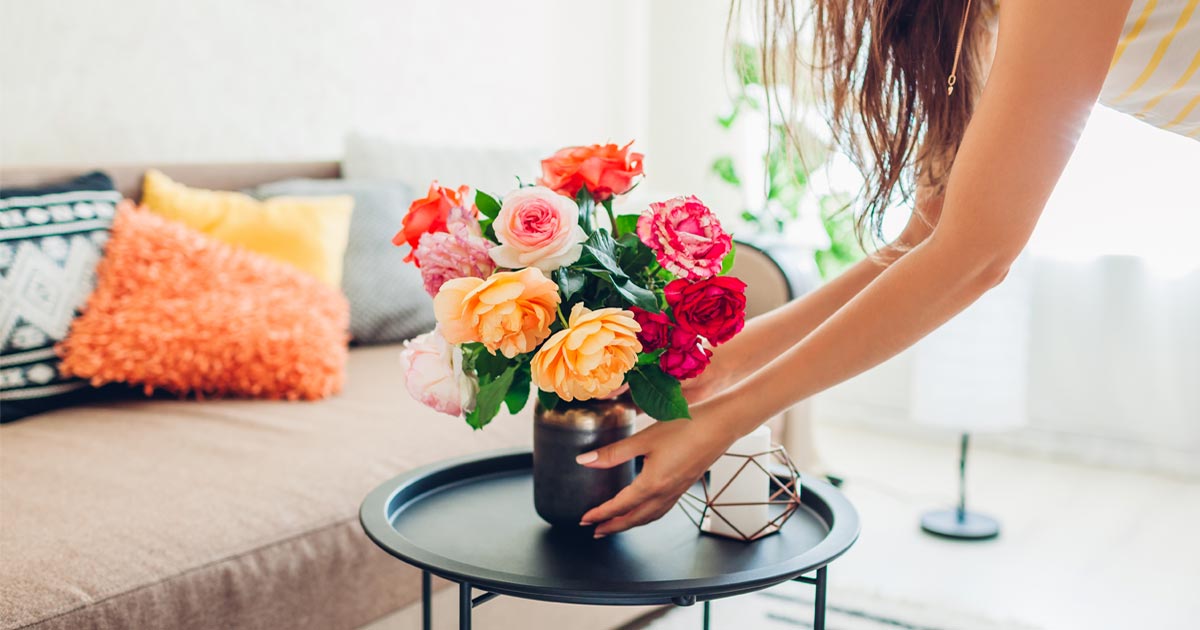 woman setting flowers on a coffee table for staging