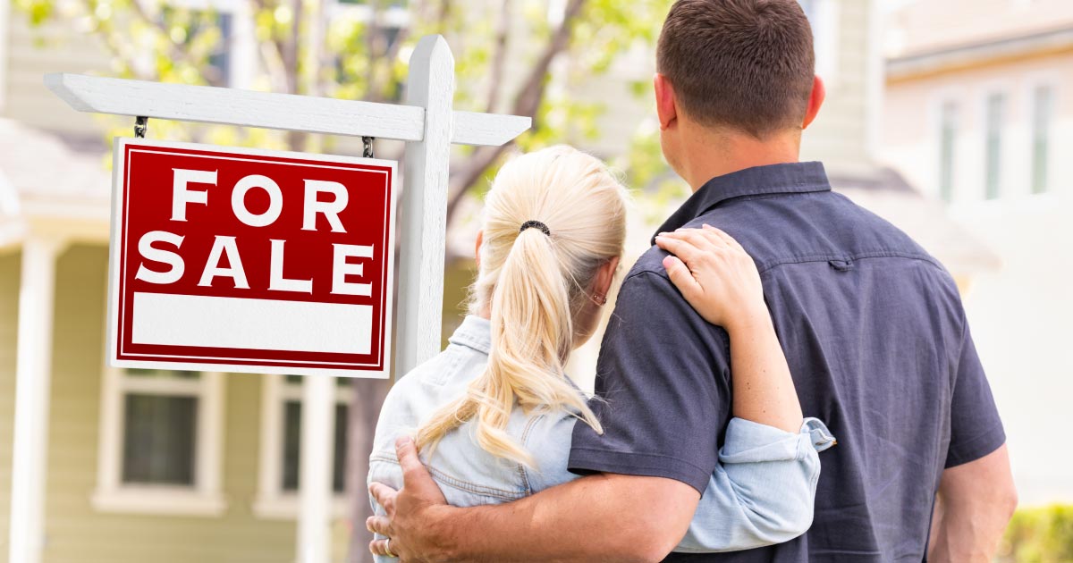 couple selling house sign in yard