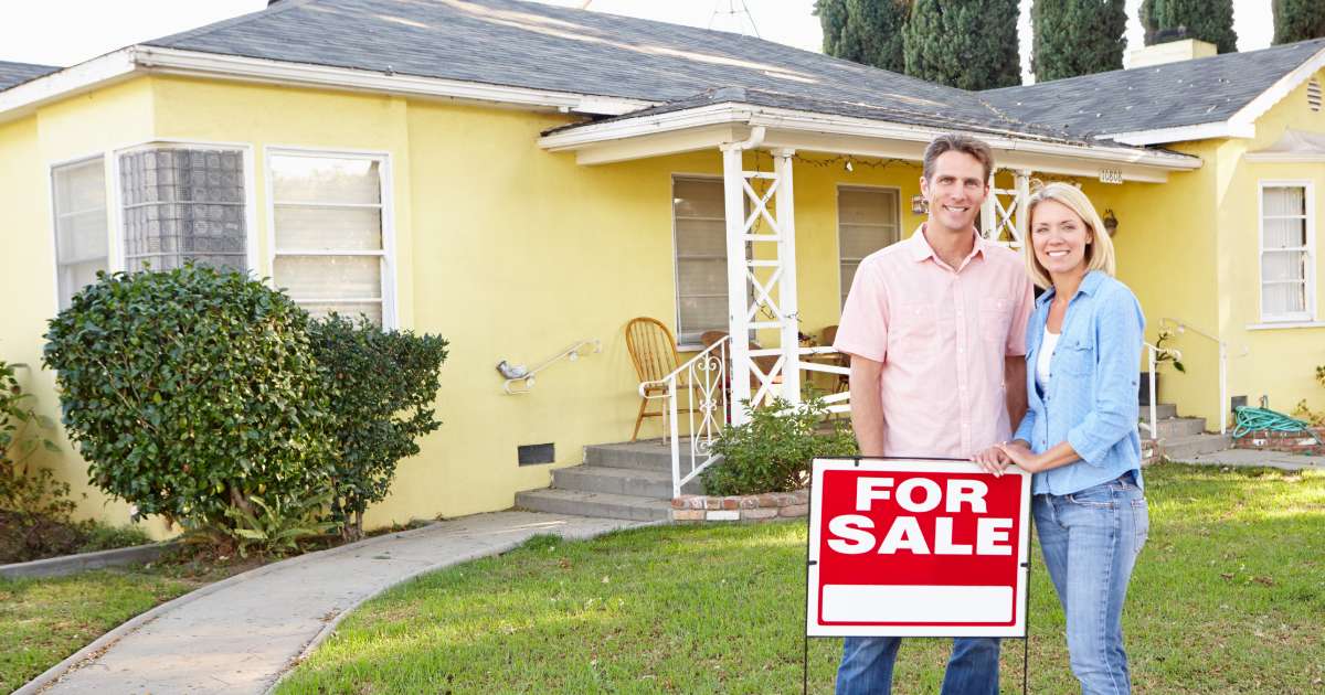 couple looking at house for sale sign