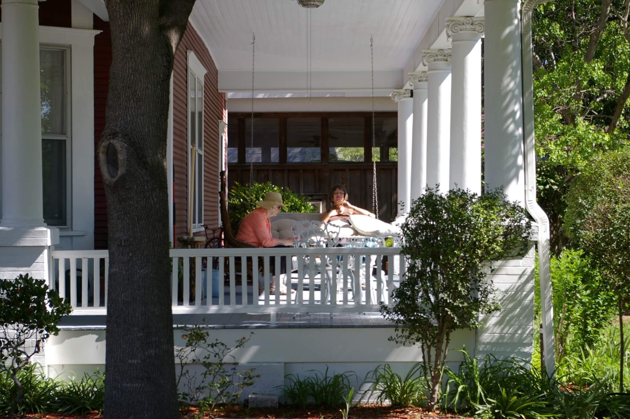 two women sitting on large white front porch
