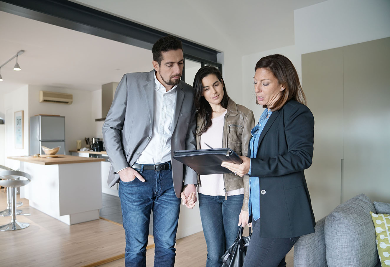 couple looking at paperwork with an agent in a house