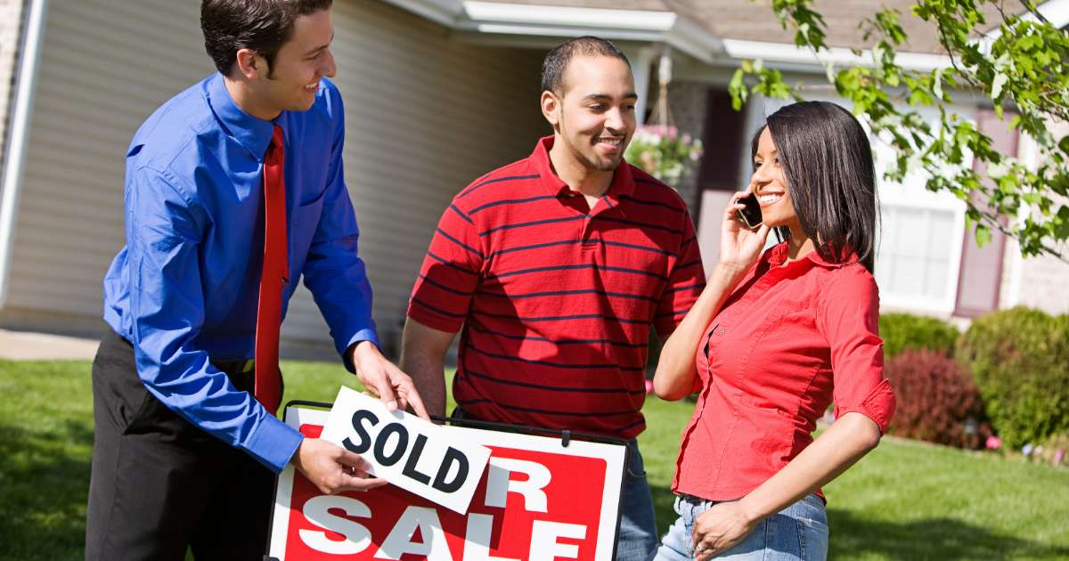 couple selling house sign in yard