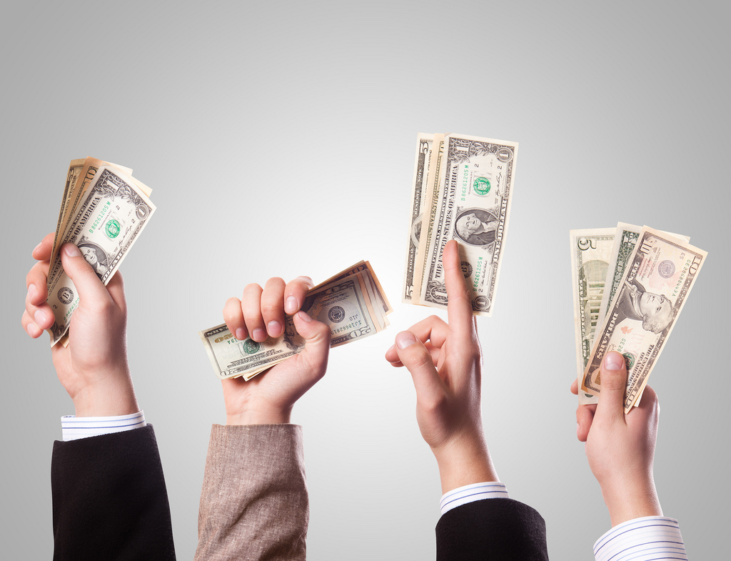 Four hands holding cash in the air.