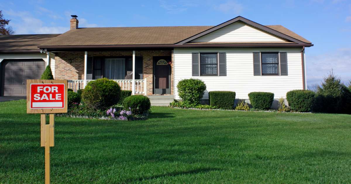 House with for sale sign in front yard