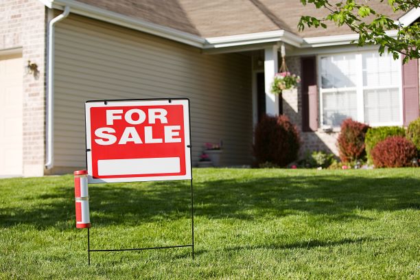 A for sale sign posted in the yard of a house.