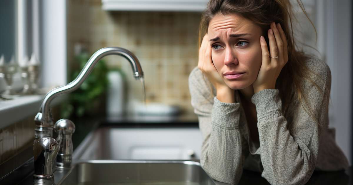 woman looking at dripping faucet